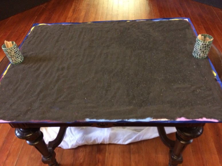 Alternated a rainbow of colored sand covered with black sand on top.